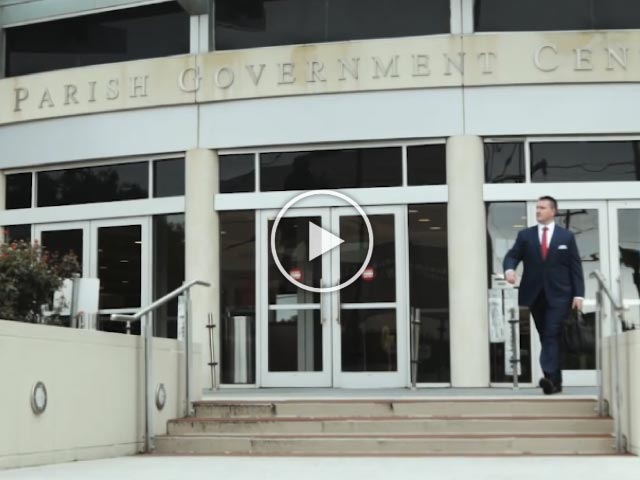 Video thumbnail graphic of Keith magness walking out of the Jefferson Parish courthouse in a navy blue suit carrying a briefcase.
